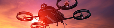 Black drone flying in the sky at sunset, lens flare
